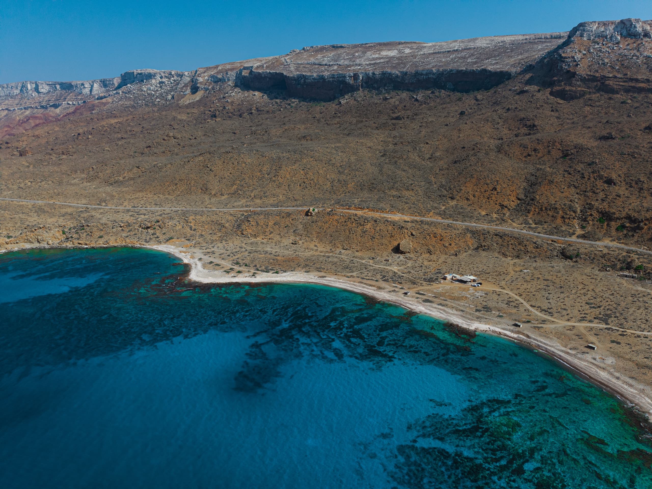 Aerial view of Socotra's turquoise reef coastline against arid mountains